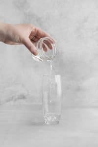 hand pouring vodka into glass