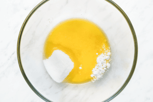 a glass bowl of melted butter, powdered sugar, and granulated sugar