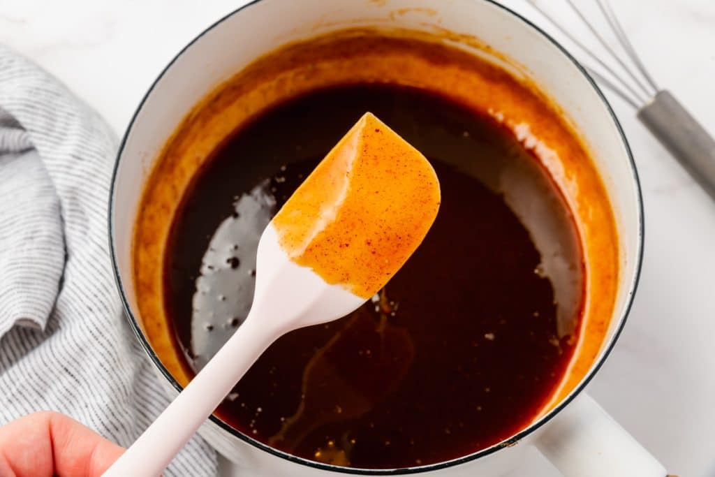 cooked pumpkin syrup in a saucepan, a spatula coated with syrup held over the pot.