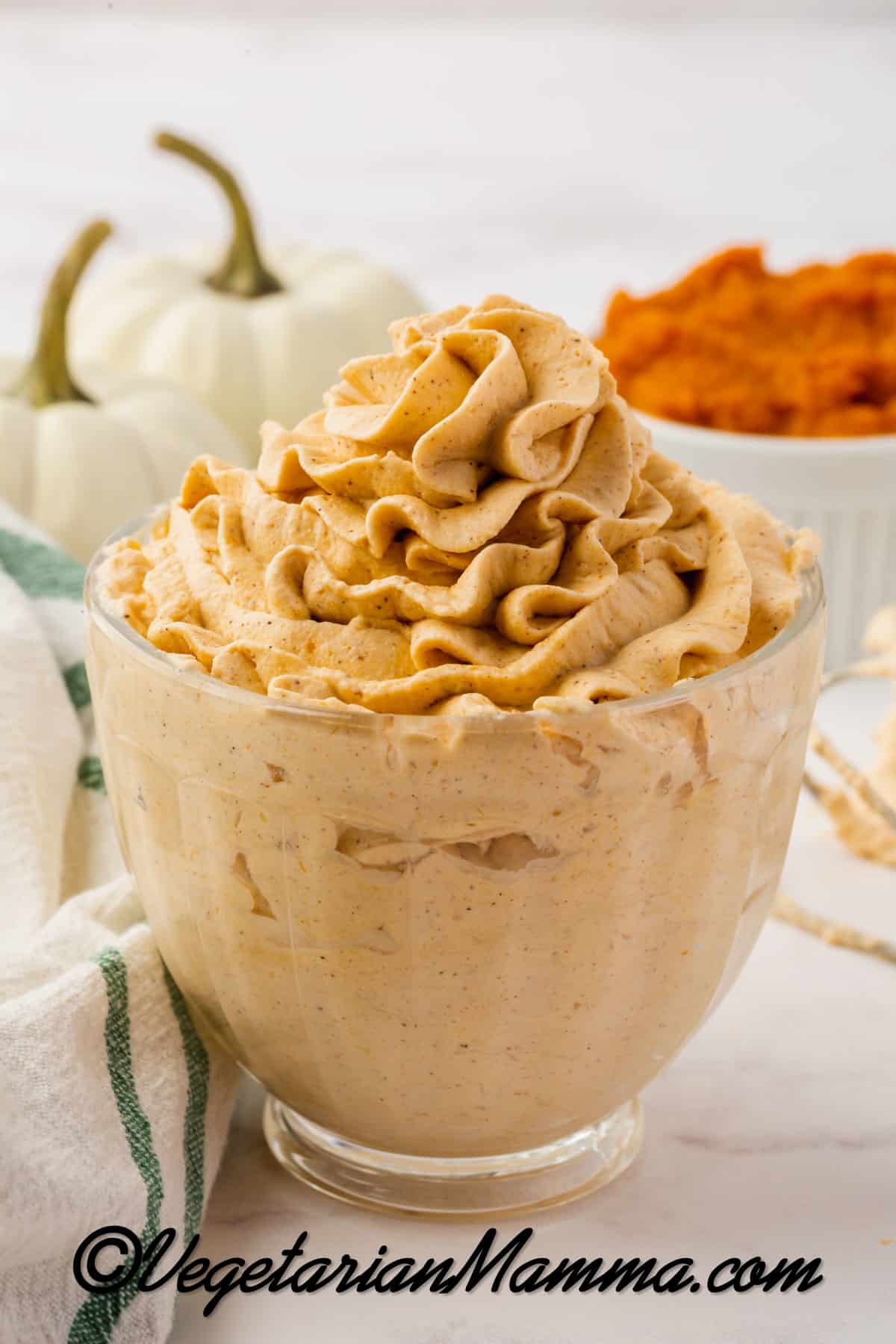 A small glass bowl filled with pumpkin whipped cream, piped into a swirl on top