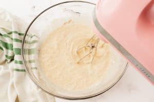 a pink mixer whipping pumpkin whipped cream in a glass bowl