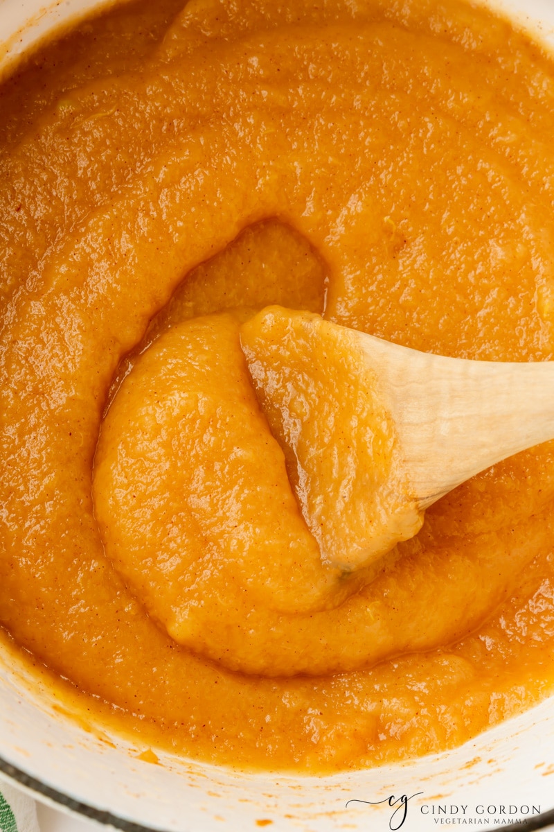 Closeup view of homemade applesauce made without sugar, swirled in a pot with a wooden spoon