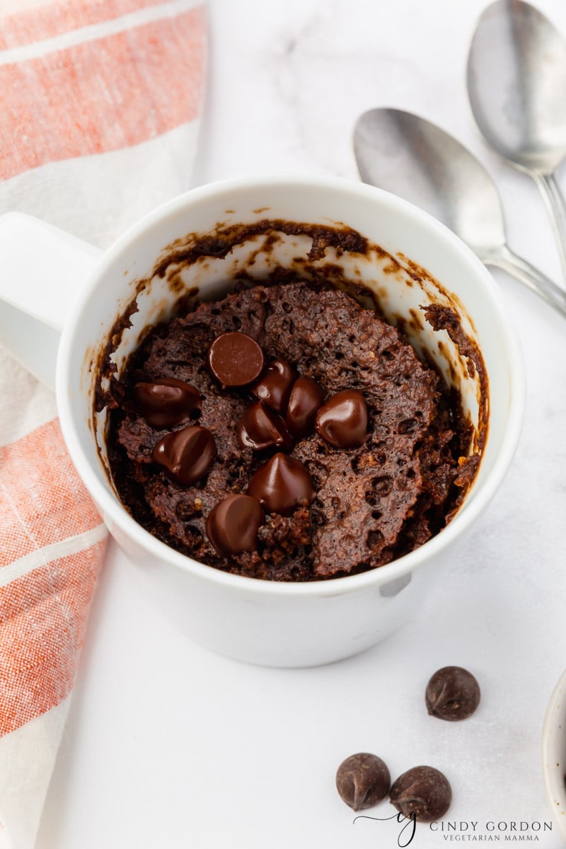 a chocolate cake made in a white mug, topped with chocolate chips