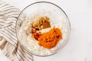 whipped cream cheese, pumpkin puree, spices and sugar in a glass bowl.