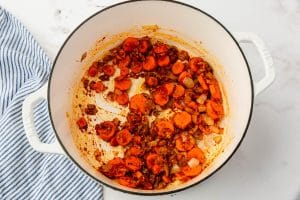 curry paste and seasonings with carrots and onions in a dutch oven