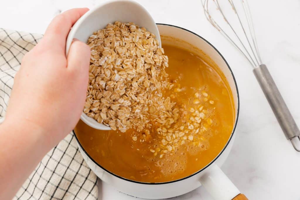 A bowl of oats being added to pumpkin spiced hot milk.