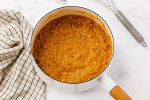 Cooked pumpkin spice oatmeal in a white saucepan.