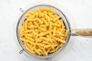 Cooked fusilli in a mesh strainer