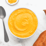 a bowl of creamy sweet potato sauce on a marble countertop, viewed from above