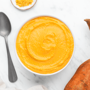 a bowl of creamy sweet potato sauce on a marble countertop, viewed from above