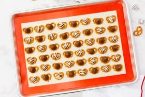 a sheet tray lined with a silpat mat, covered with mini pretzels. Each is topped with a hershey's kiss or hug.