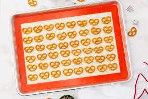 a sheet pan covered with a silpat mat. 5 rows of mini pretzels are arranged on it.