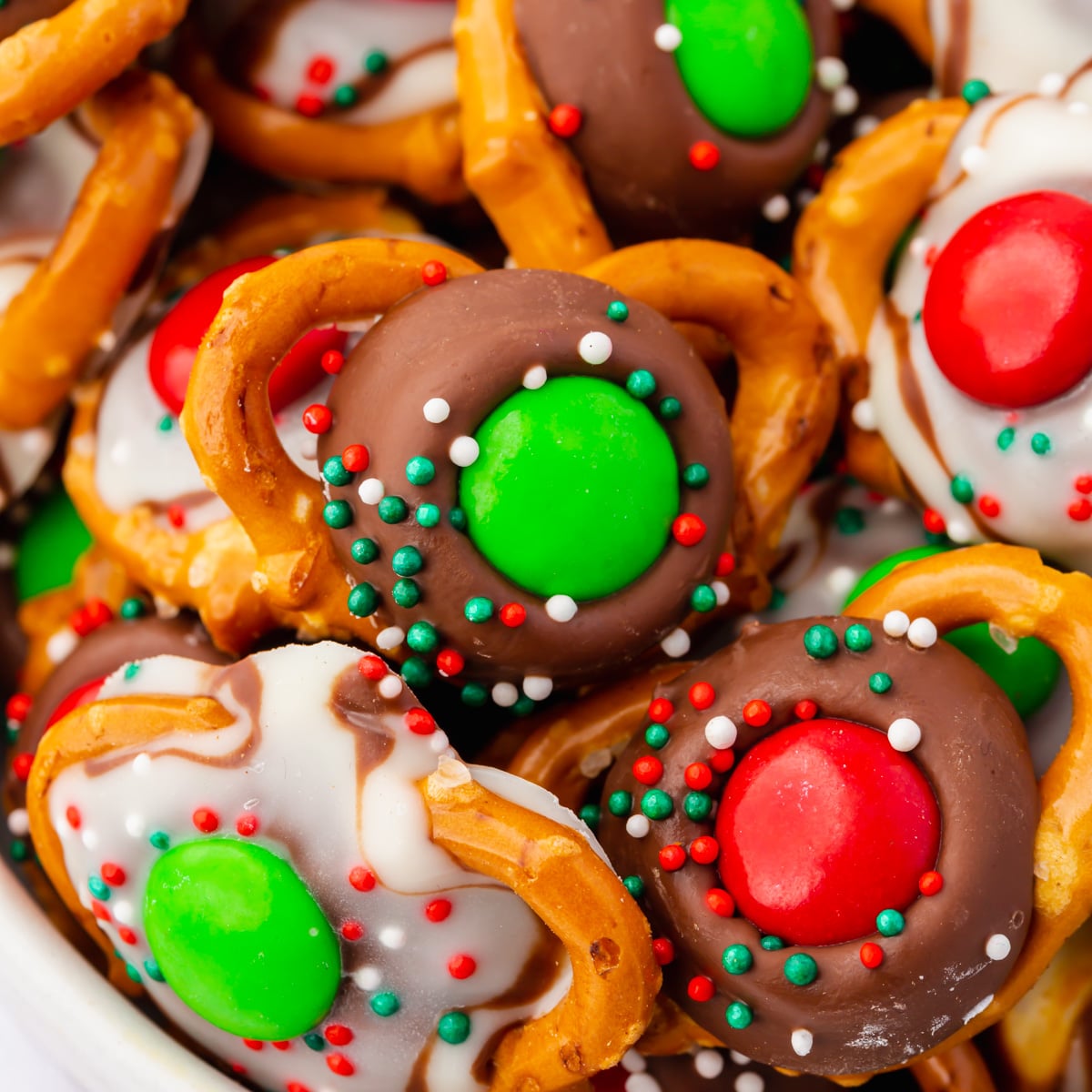 Christmas Pretzels. mini gluten free pretzels topped with melted chocolate kisses, holiday m&ms, and nonpareil sprinkles.