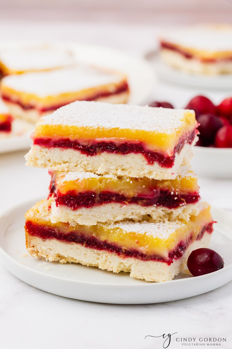 A stack of three gluten free cranberry lemon bars on a plate.