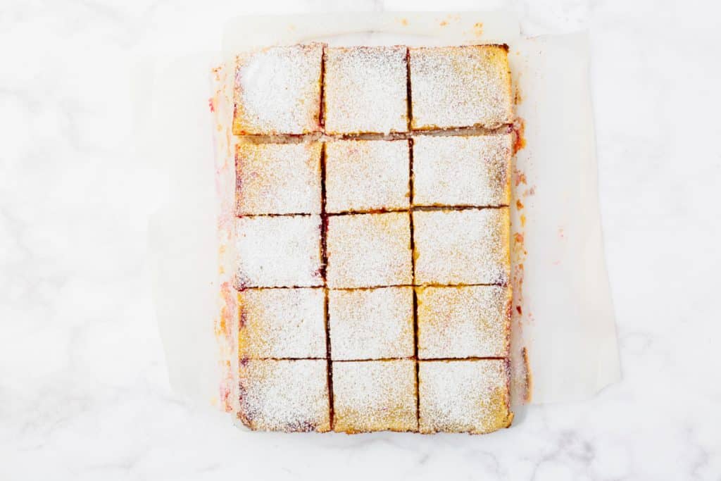 cranberry lemon bars cut into squares and sprinkled with powdered sugar