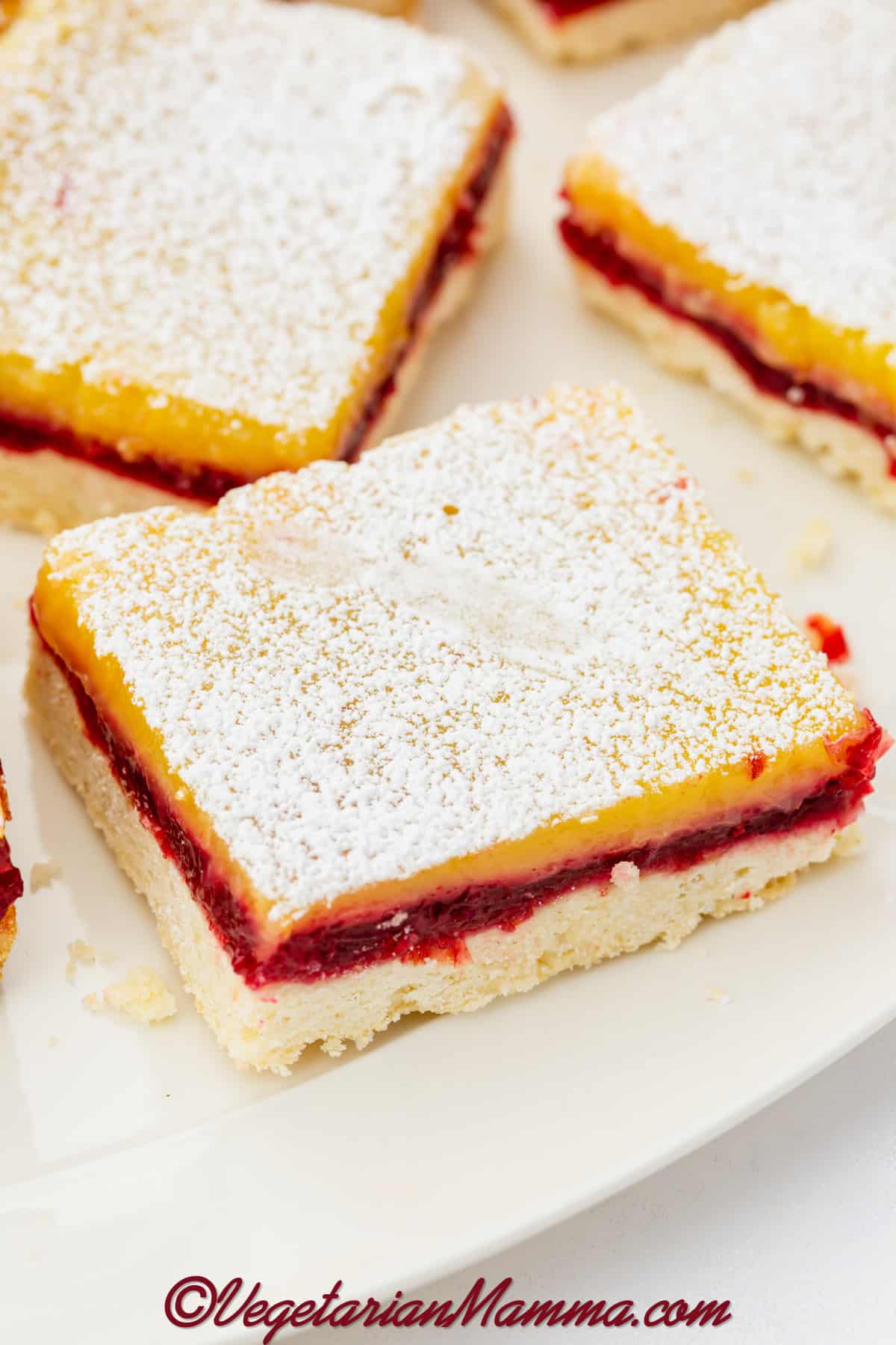 cranberry lemon bars sprinkled with powdered sugar in a single layer on a platter.