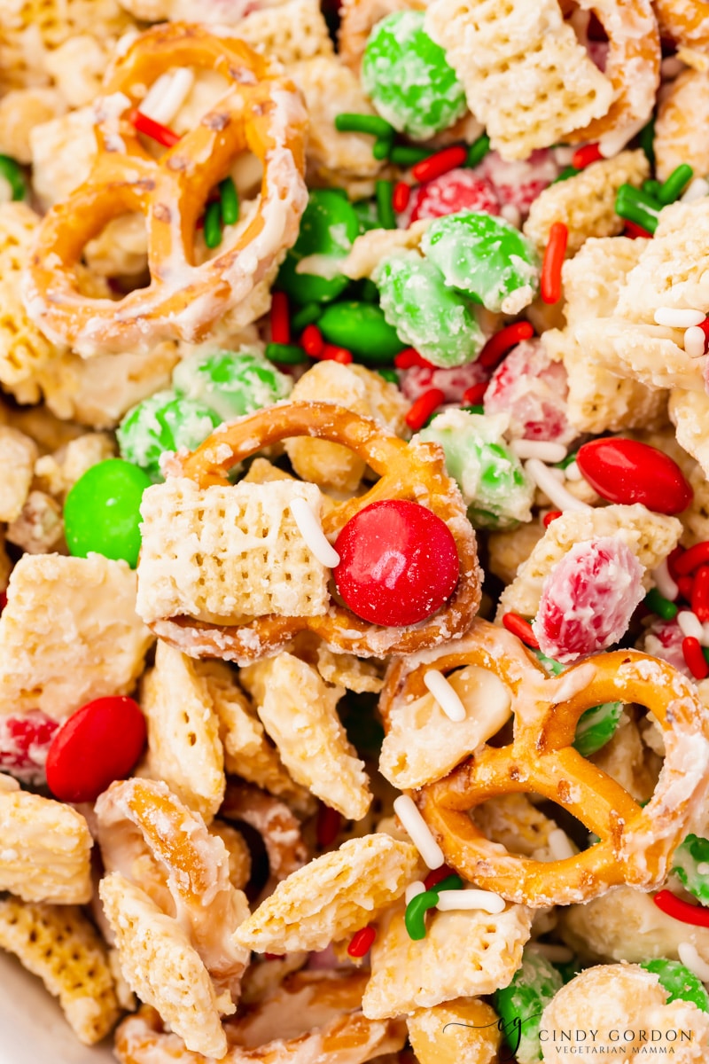 Closeup view of chex, pretzels, peanuts and m&ms coated with white chocolate.