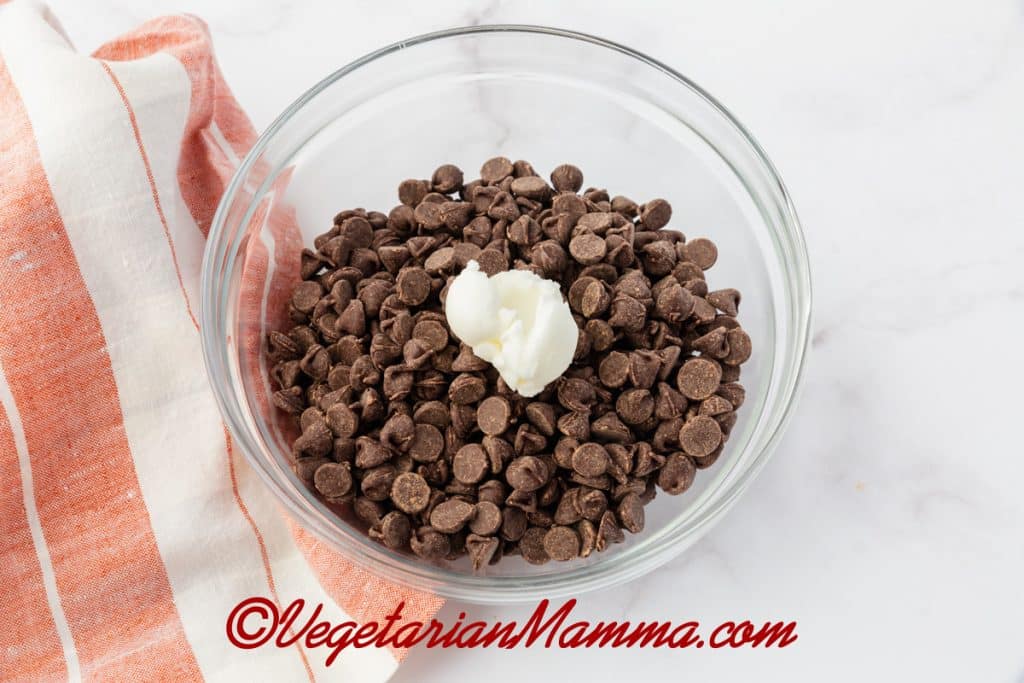 Chocolate chips and vegetable shortening in a glass bowl.