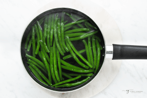 whole fresh green beans in a pot of boiling water, viewed from above.