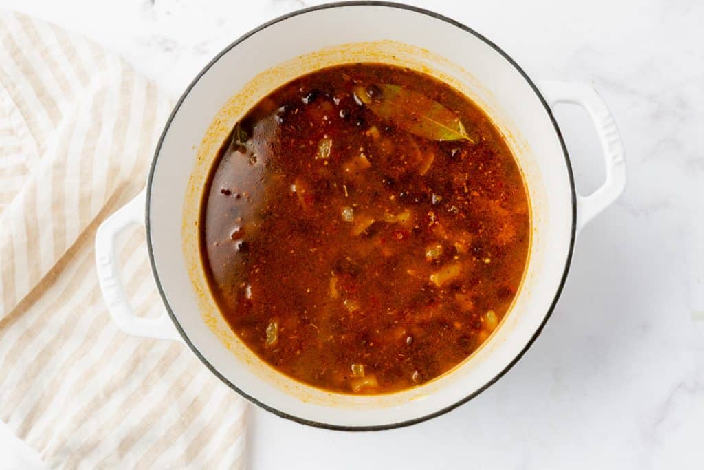 Simmering seasoned black beans in a white dutch oven.