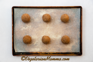 Shape the cookie dough into balls. Roll each ball in cinnamon sugar.