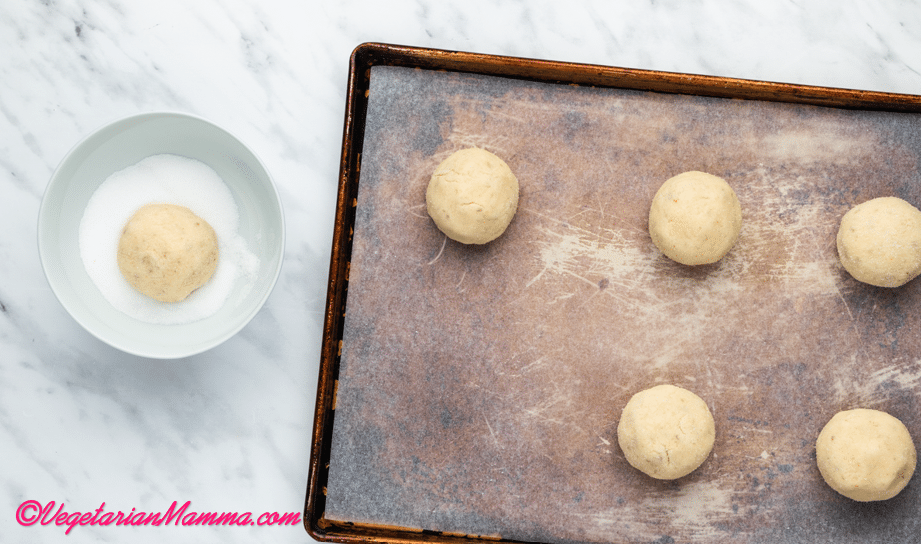 Roll the cookie dough into balls and dip each in the bowl of sugar to coat it.