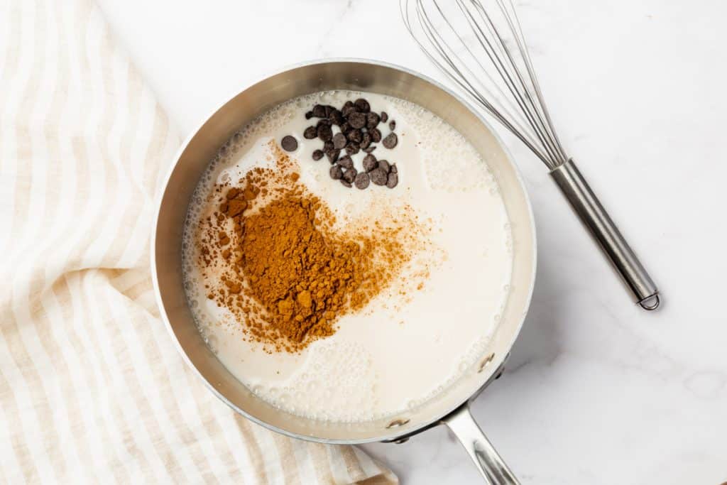 almond milk and cocoa powder in a saucepan. A whisk is next to it.