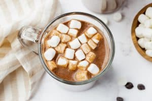 A glass mug of vegan hot chocolate with vegan marshmallows on top