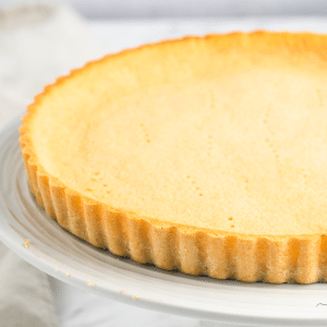 a coconut flour pie crust on a white cake pedestal.