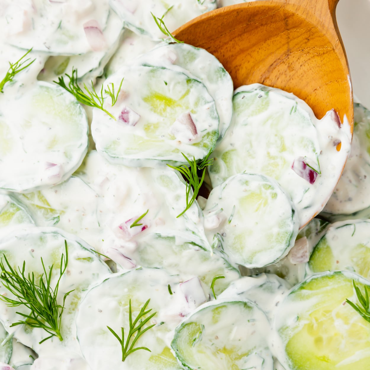 polish cucumber salad in a serving bowl with a large spoon.