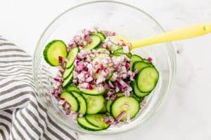 Sliced cucumbers and red onions added to sour cream.
