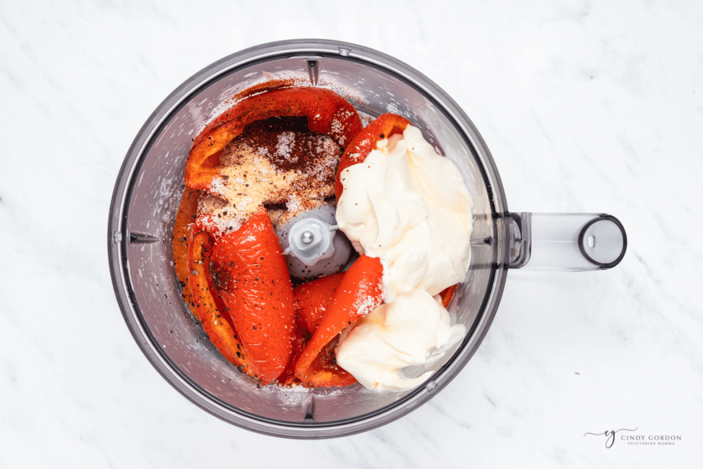 roasted red peppers and sour cream with seasonings, in a food processor bowl, viewed form above.
