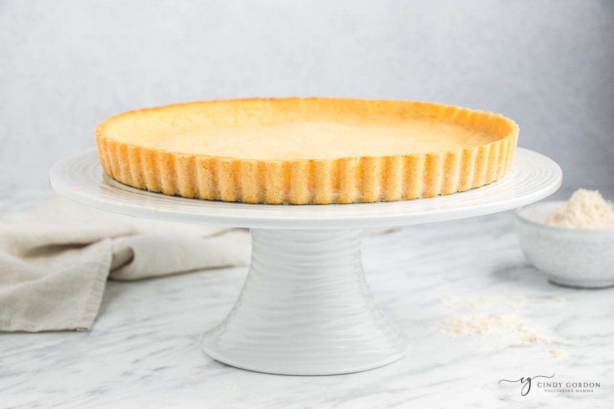 a coconut flour pie crust on a white cake pedestal.