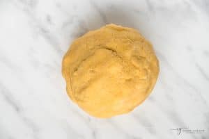 a ball of coconut pie crust dough on a marble counter