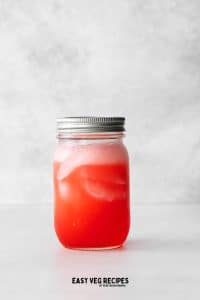ball jar full of red liquid and ice cubes with a lid