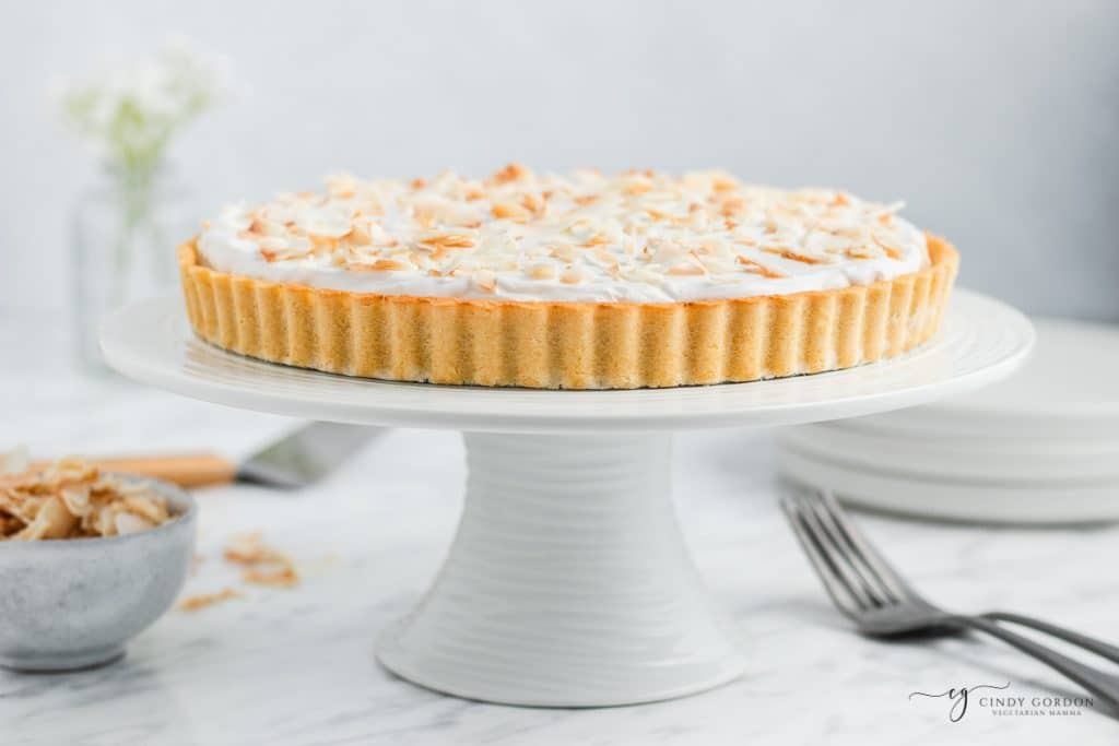 coconut cream pie on a white cake stand.