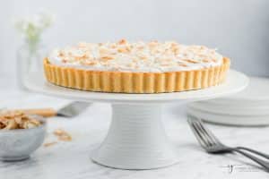 coconut cream pie on a white cake stand.