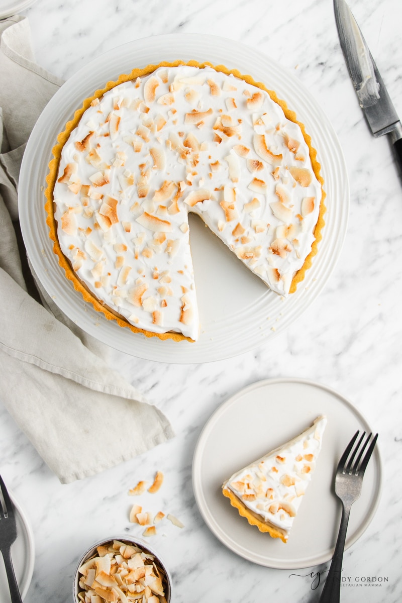 overhead image of a vegan coconut cream pie. A slice has been removed and placed on a small plate with a fork. 