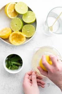 a hand juicing lemons and limes, viewed from overhead