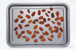 Pecan halves spread out on a baking sheet for toasting.