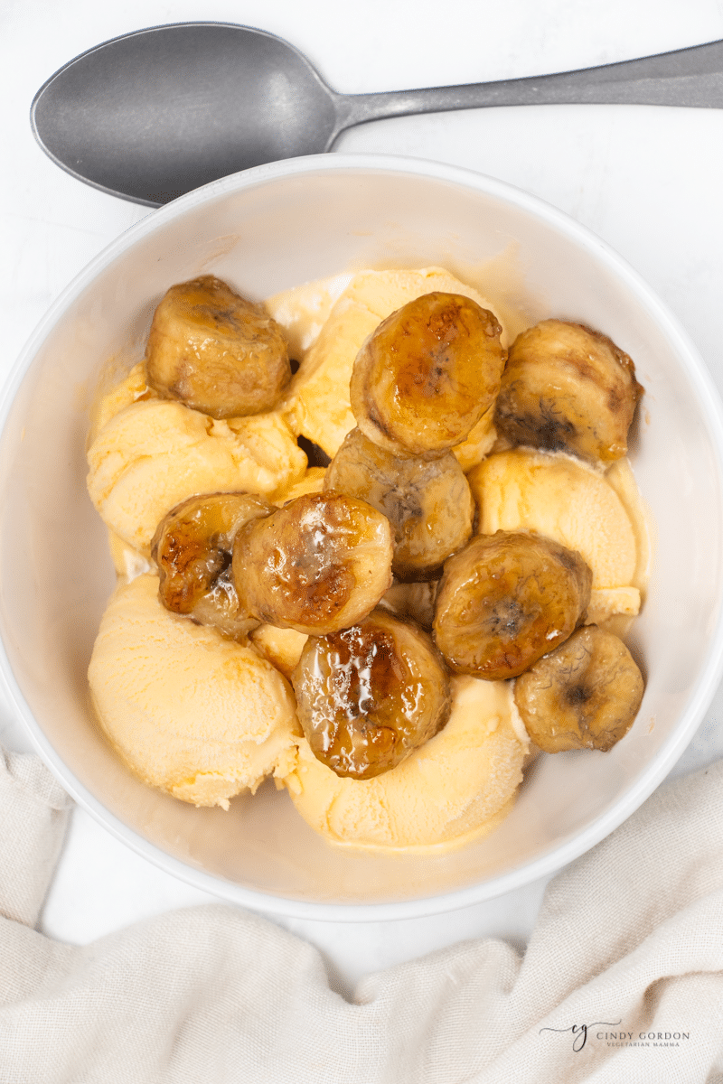 a bowl of vanilla ice cream topped with cooked caramelized bananas