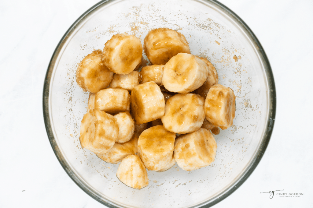 sliced banana coins in a glass bowl with brown sugar.