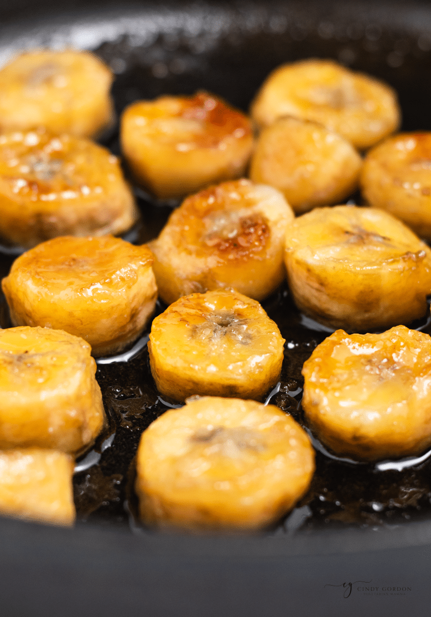 close up of banana slices caramelizing in a frying pan. 