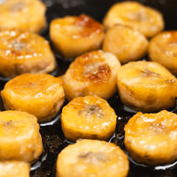 close up of banana slices caramelizing in a frying pan.