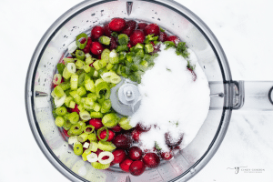 a food processor holding green onion, jalapeno, sugar and fresh cranberries.