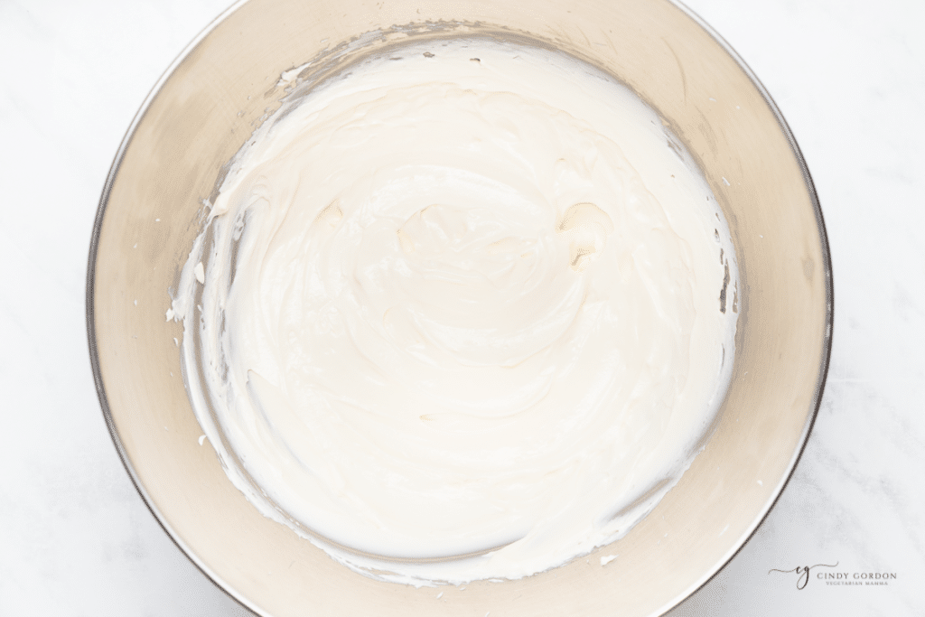 cream cheese that has been whipped in a stand mixer bowl.