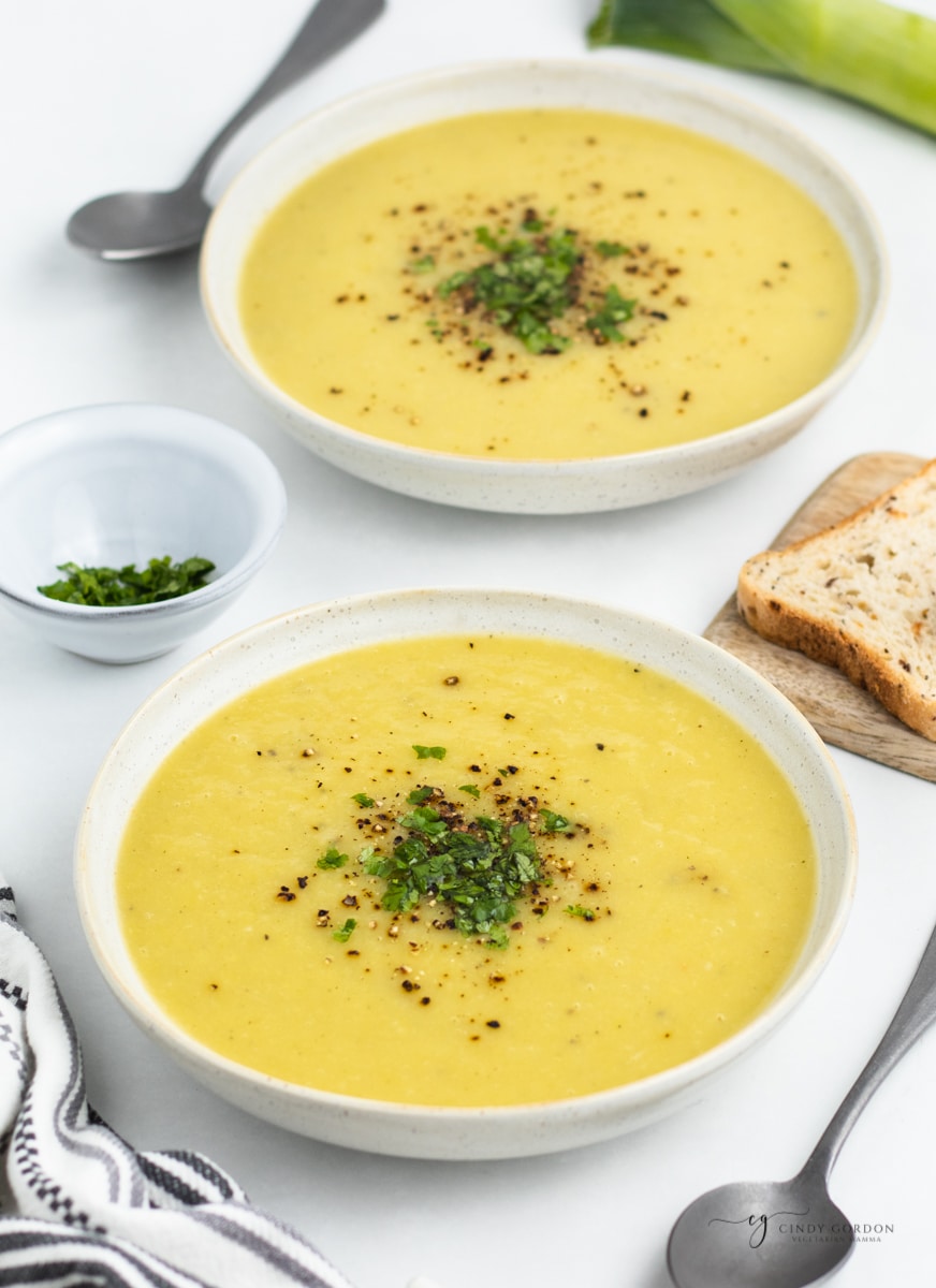 two bowls of smooth and creamy magic leek soup garnished with pepper and parsley.