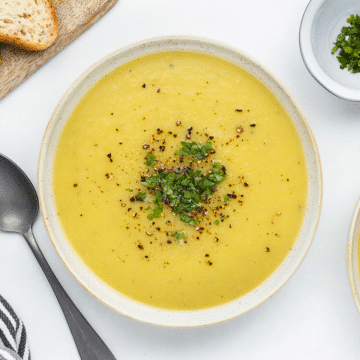 a bowl of smooth and creamy magic leek soup garnished with pepper and parsley.