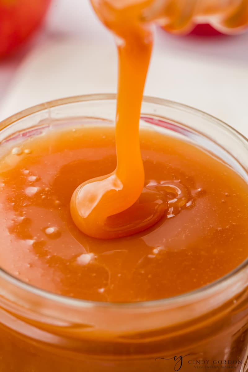 closeup view of a small jar filled with caramel sauce.
