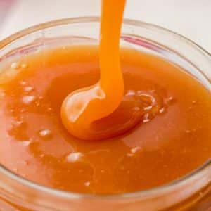 closeup view of a small jar filled with caramel sauce.